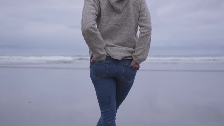 A woman is walking on the beach outdoors