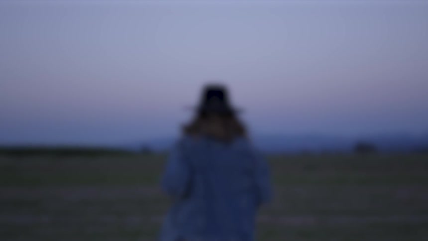 Woman wearing a brimmed hat runs in a field