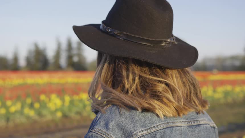 A young woman walks through a field of flowers