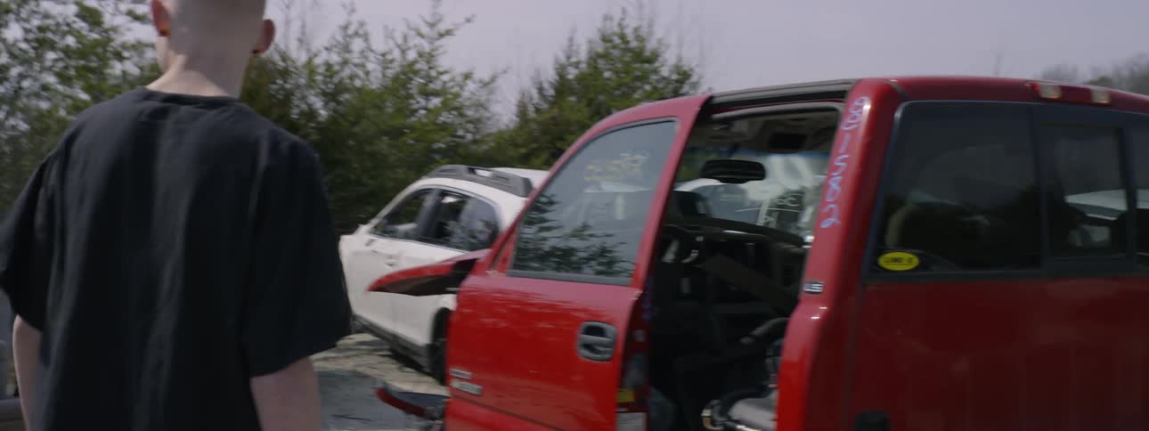A man walking through a junkyard of cars