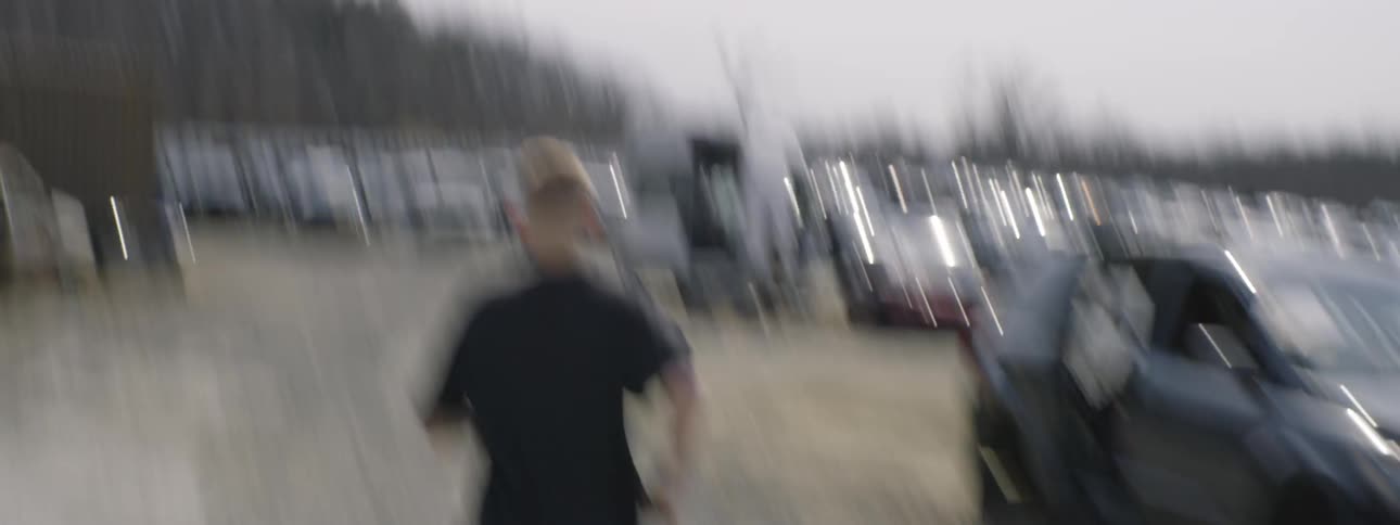 A young boy running towards a junkyard