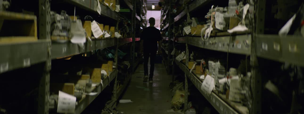 A boy walking down a hallway full of items