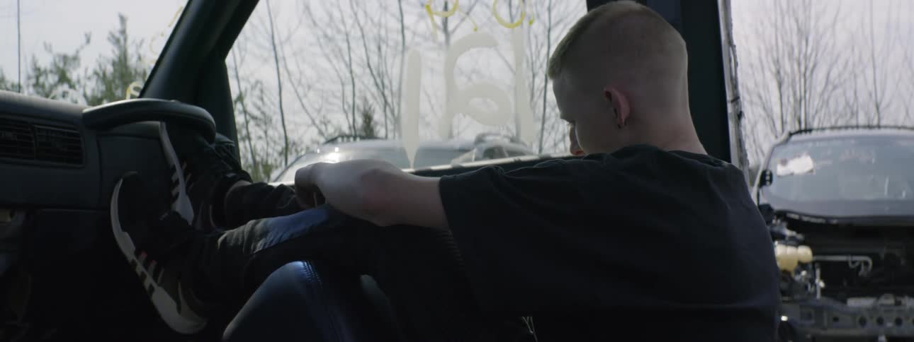 A boy sitting in a deconstructed car