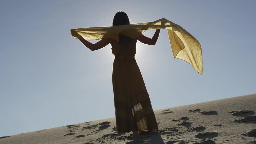 A woman holds her scarf to the wind