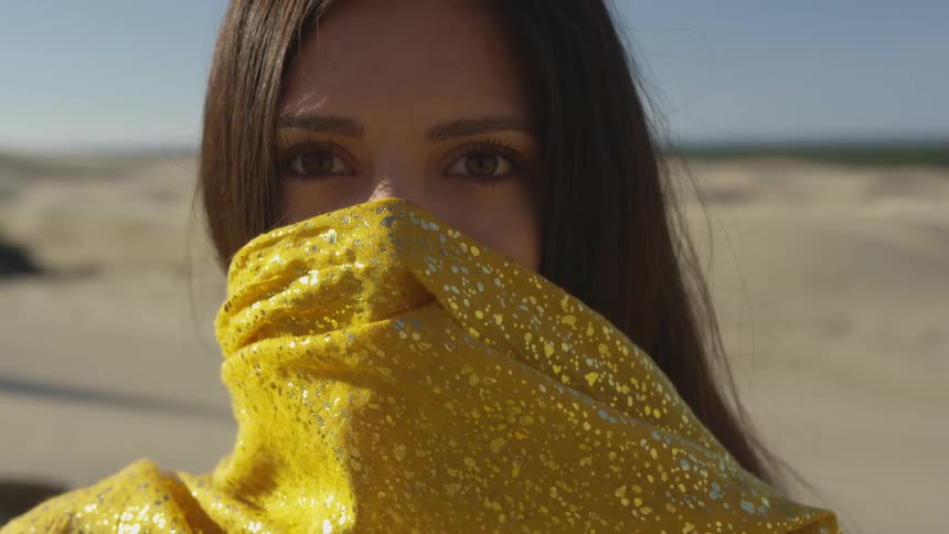 A young woman covers her face with a scarf