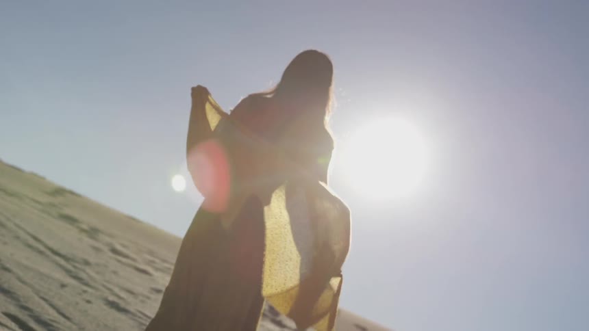 A woman holds her scarf into the wind