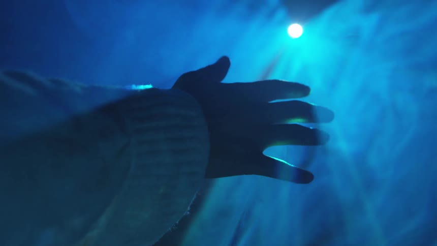 A person holds their hand in a beam of light