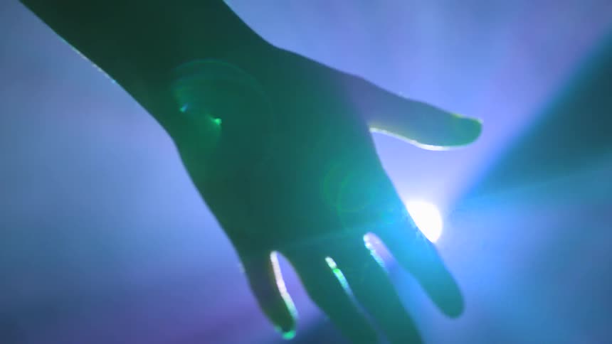 A hand open in front of a stage light