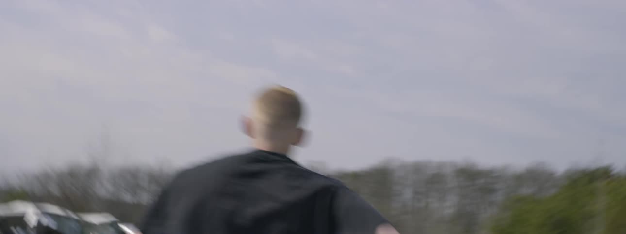 A teenage boy runs through a junkyard full of wrecked cars