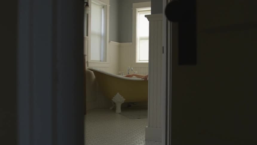 Person soaking in claw foot tub in bathroom in daytime