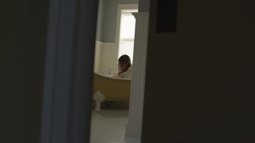 A woman sits in the bathtub