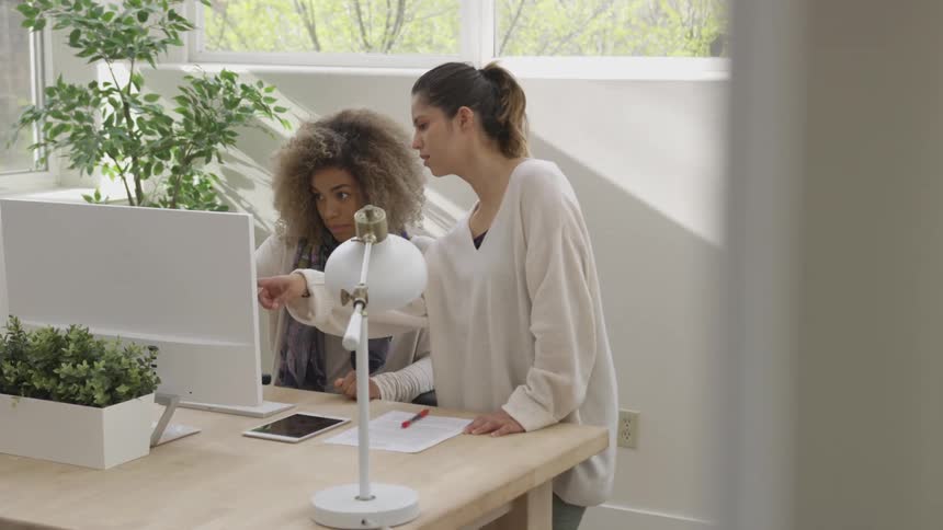 Two women are working on electronics at a desk