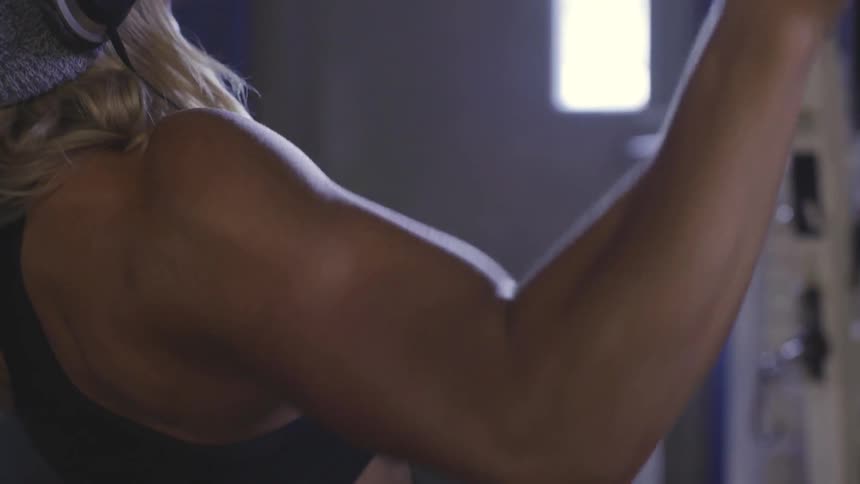 A white female exercising her arms with a pulldown machine