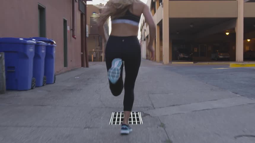 A white female runner running down an alleyway
