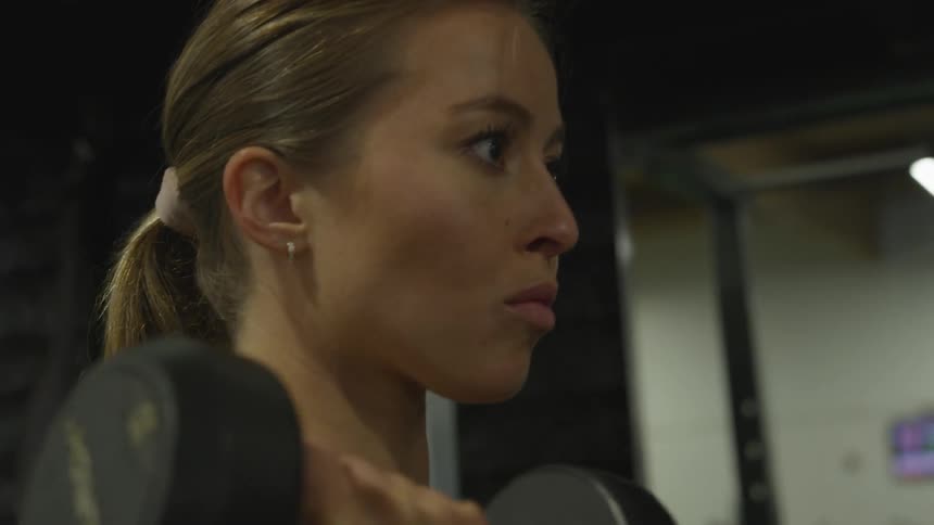 White woman lifting dumbbells at the gym