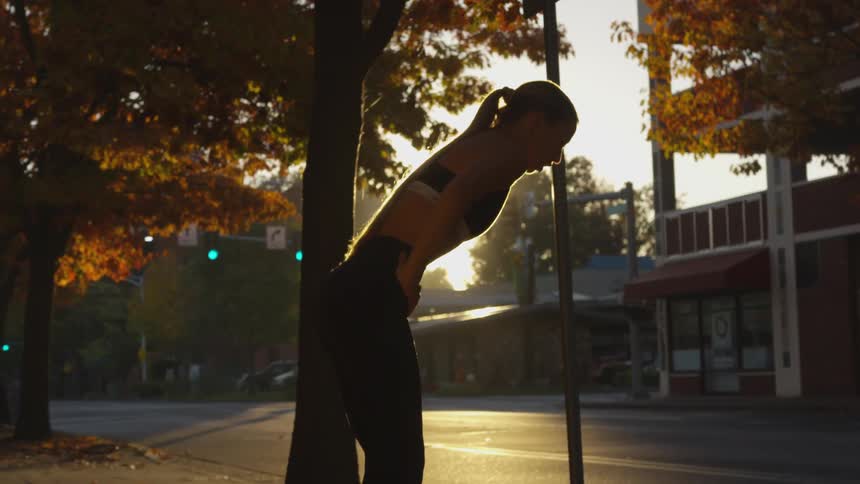 Young woman in running apparel stops to catch breath outdoors