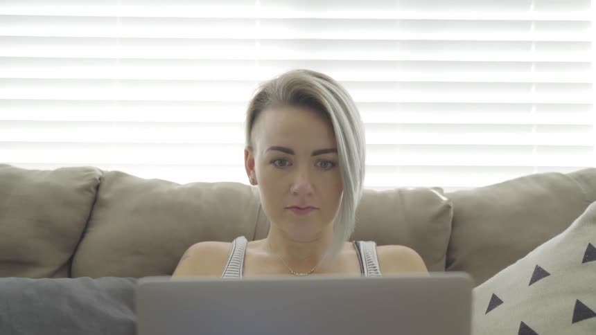A woman sitting on a couch using a laptop computer