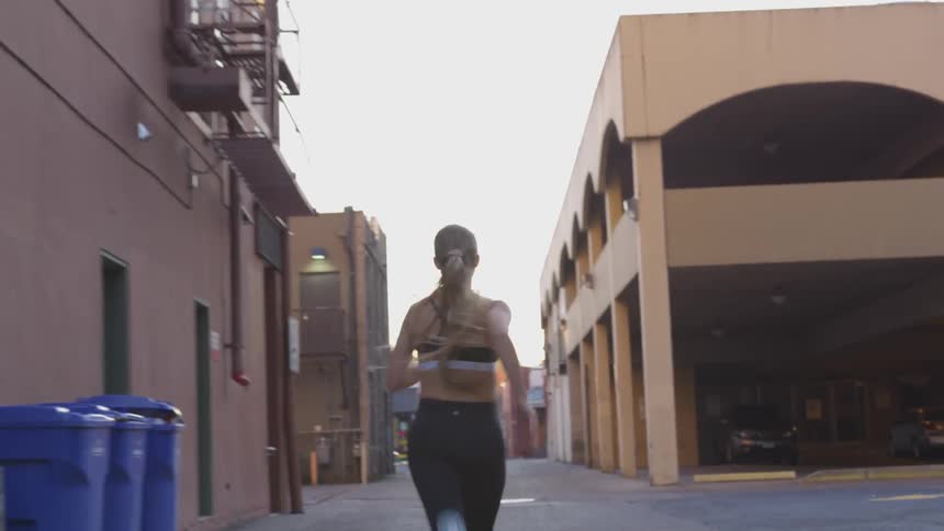 White woman running in an empty street in the middle of a city