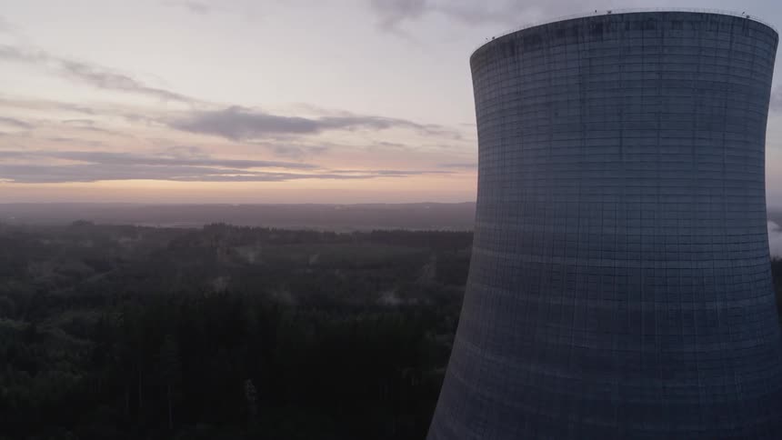 Flying toward and alongside a nuclear cooling tower at sunset