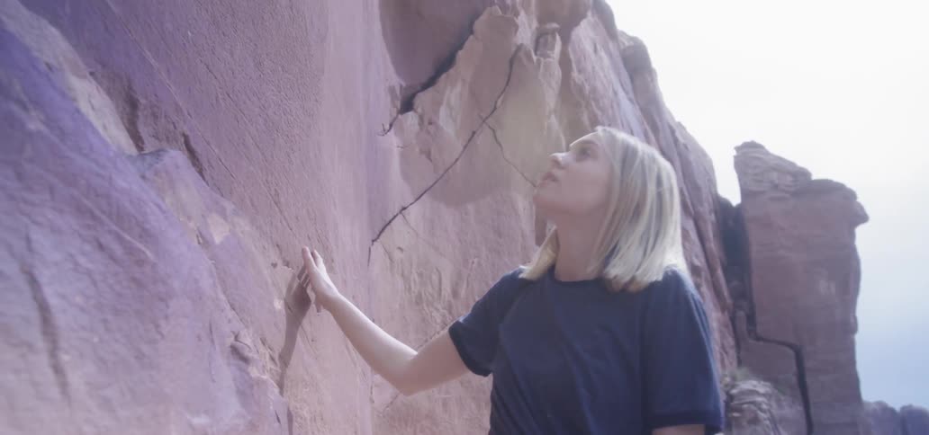 A woman brushes her hand along a canyon
