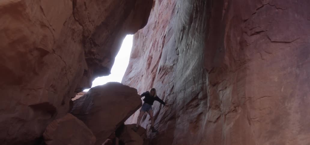 A young woman climbs through rocks