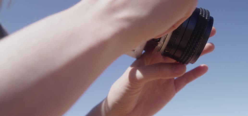 A woman lifts a camera to her face