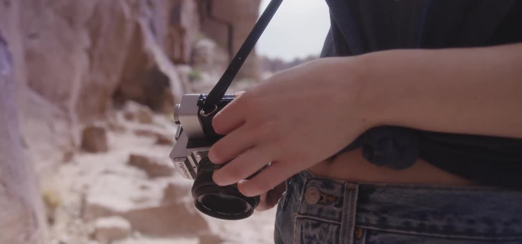 A woman is holding a camera outdoors