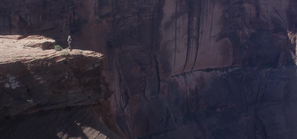 A person walking to the edge of a cliff