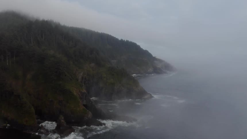 Fog rises above the ocean next to the coast