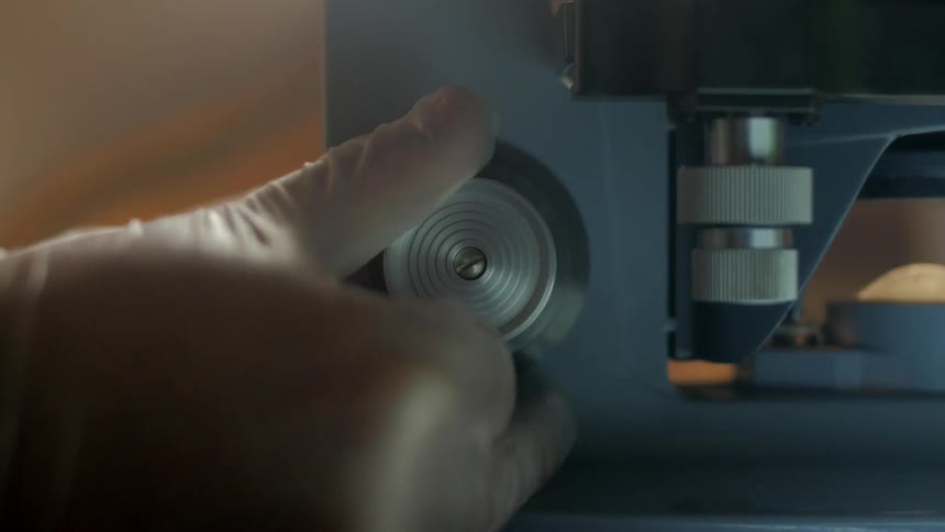 A man adjusts a wheel on a piece of scientific equipment