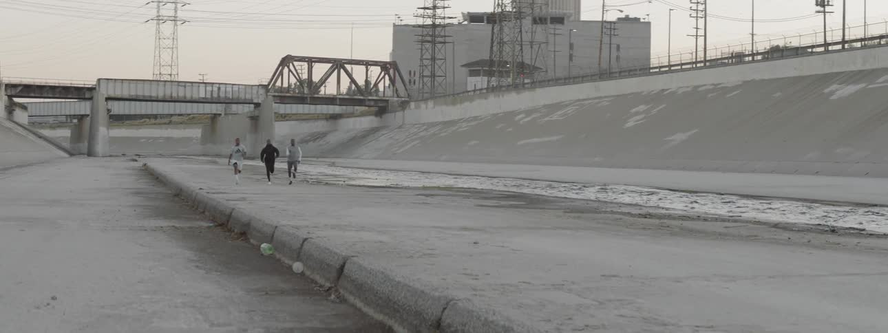 Three black men race each other in a concrete river basic