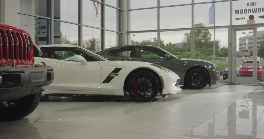 The camera looks at cars in a showroom