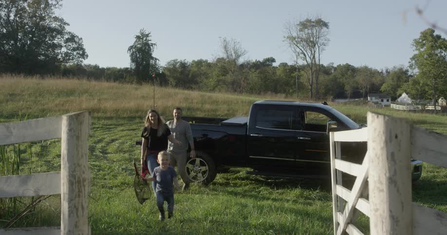 A family leaving their vehicle and walking through a wooden gate