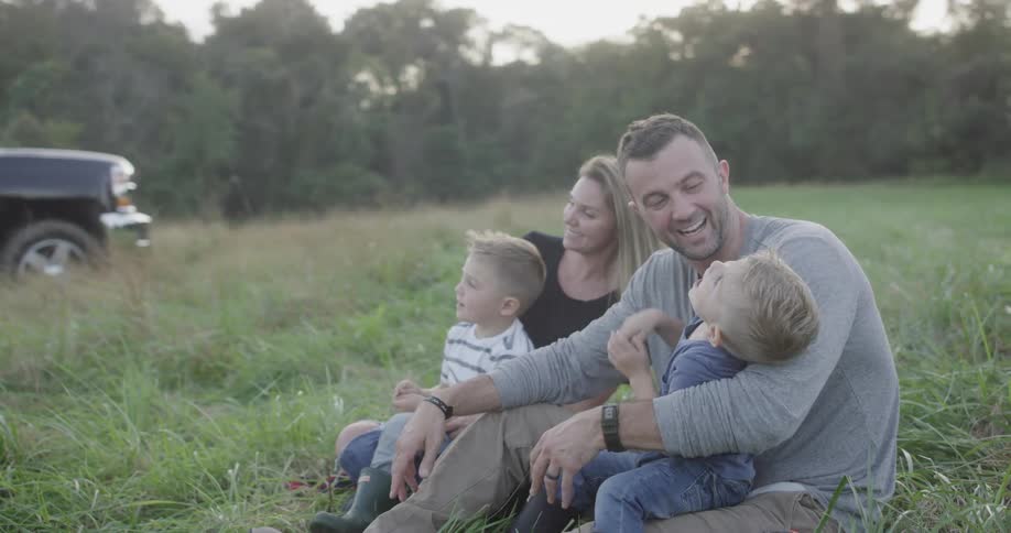 A family is sitting in the grass together