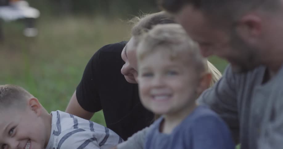 A family is outside sitting in the grass