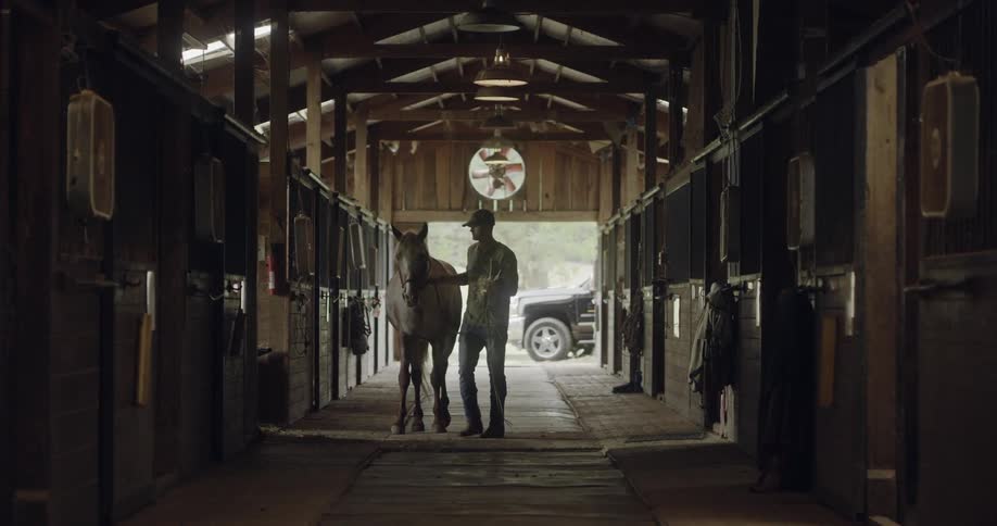 A man leads his horse in to a stable