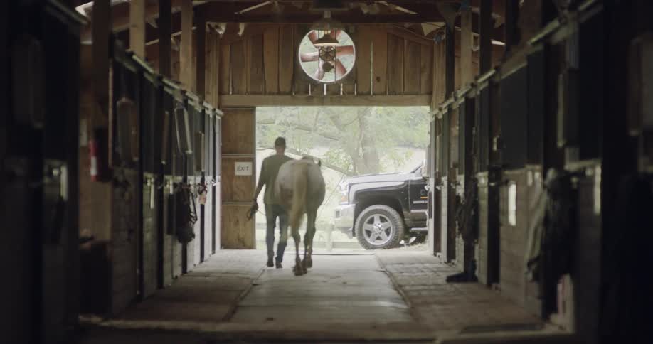A man leads a horse out of the barn