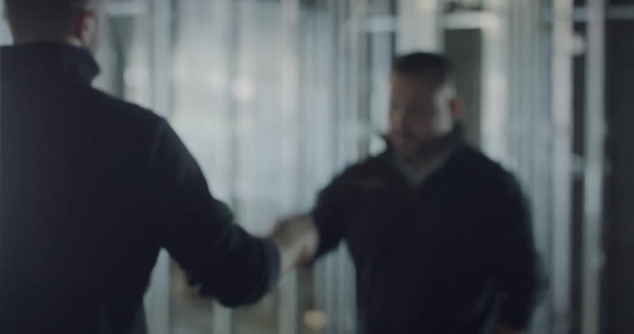 Two men in a construction site greeting each other