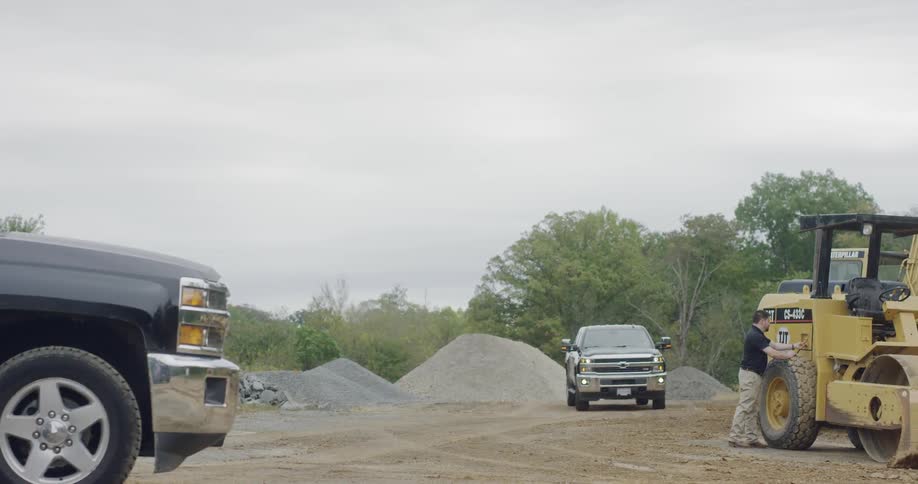A pickup truck drives through a gravel lot