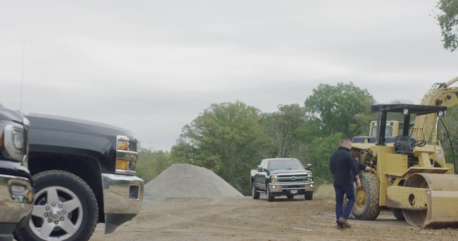 The vehicle approaches the excavation site with people on a cloudy day