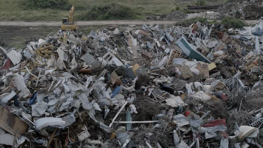 Bulldozer sits in the field next to the garbage dump