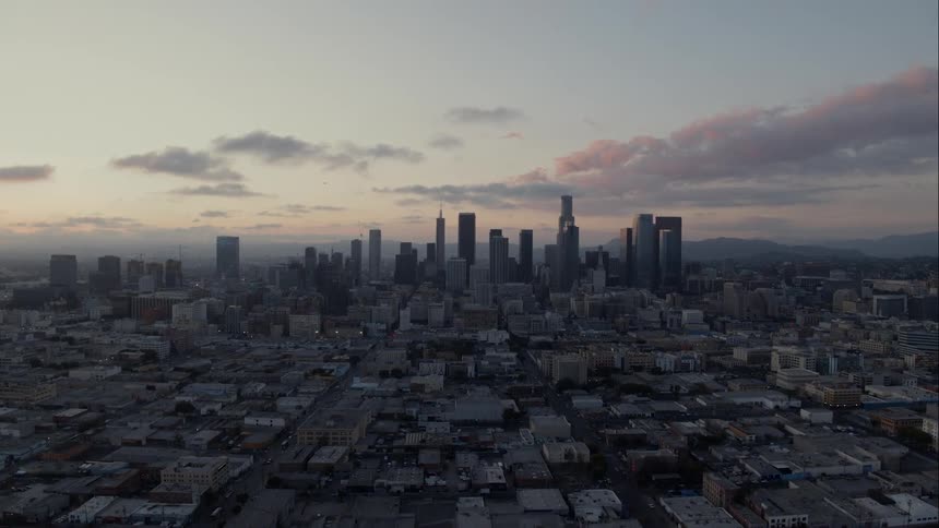 Clouds float over city skyscrapers at sunset