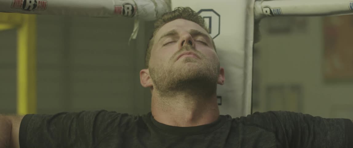 A man sitting in a boxing ring with his head tilted back