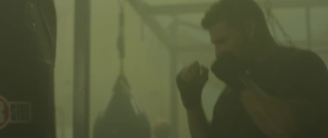 A man is punching the heavy bag in the gym