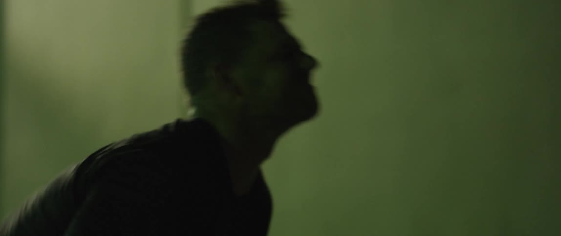 A man in a dark room flipping a tire for exercise