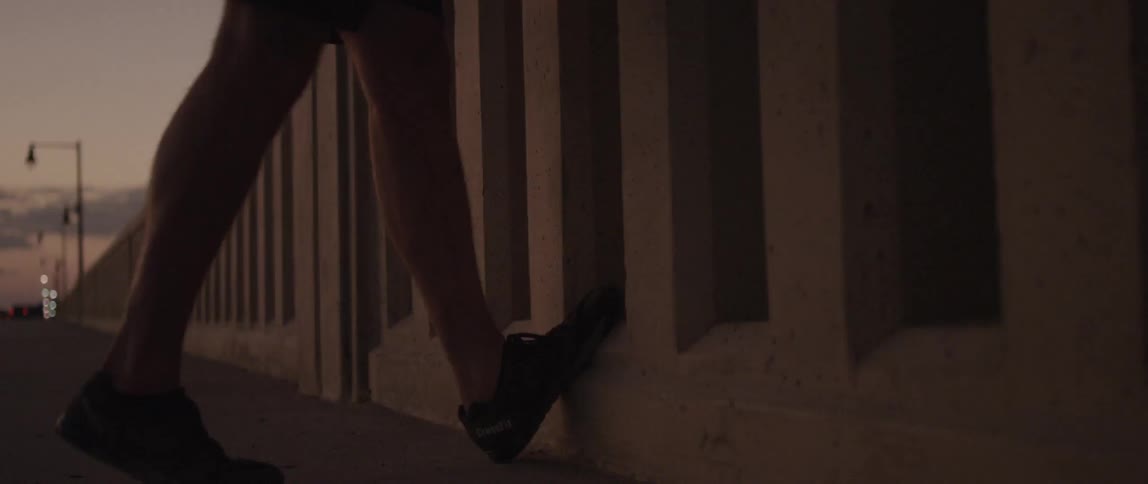 A man stretches his calves on a concrete railing