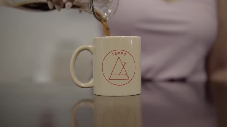 A woman pouring coffee into a mug