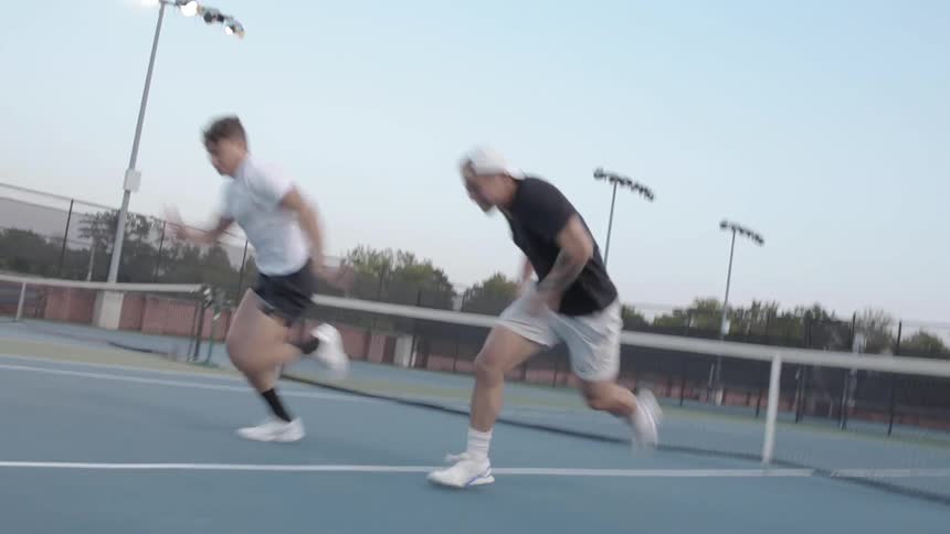 Two young men run a race on a tennis court