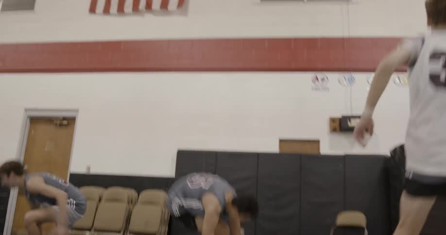 A boys basketball team doing suicide running drills in a gymnasium