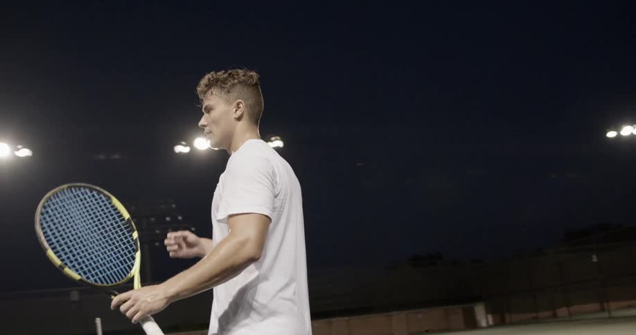 A tennis player is wiping his face and turning to the side